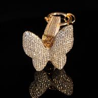 Crystal butterfly keychain and purse charm with polished gold-tone hardware on a black reflective background.