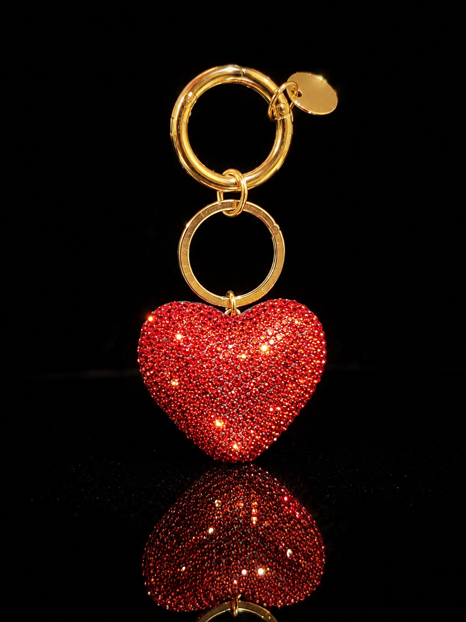Red crystal heart keychain and purse charm with gold-tone hardware on a black reflective background.