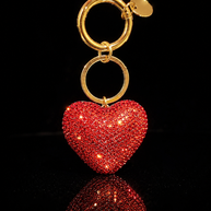 Red crystal heart keychain and purse charm with gold-tone hardware on a black reflective background.