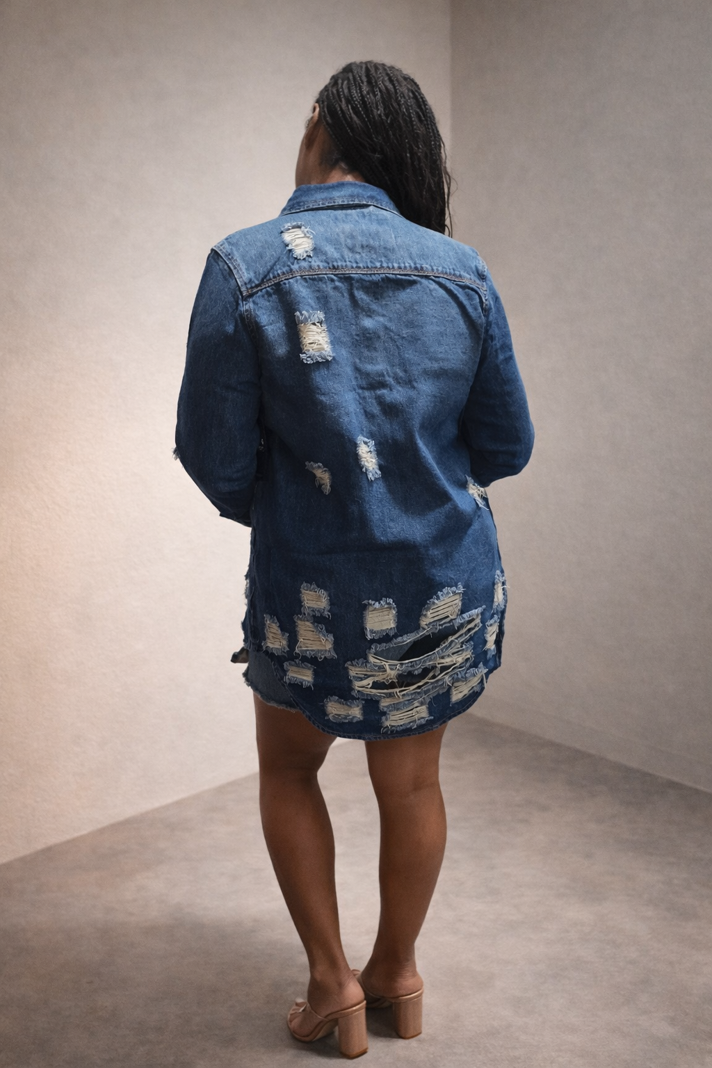 Back view of distressed denim jacket with frayed detailing and structured silhouette