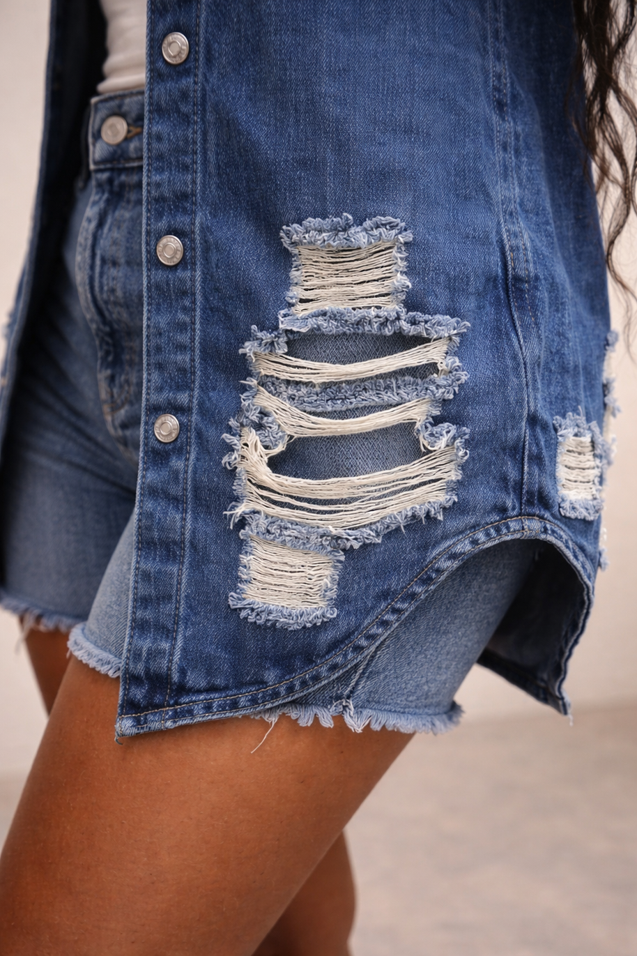 Close-up of distressed denim fabric with frayed rip detailing on jacket