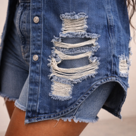 Close-up of distressed denim fabric with frayed rip detailing on jacket