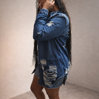 Side view of women’s distressed denim jacket with raw hem and ripped detailing